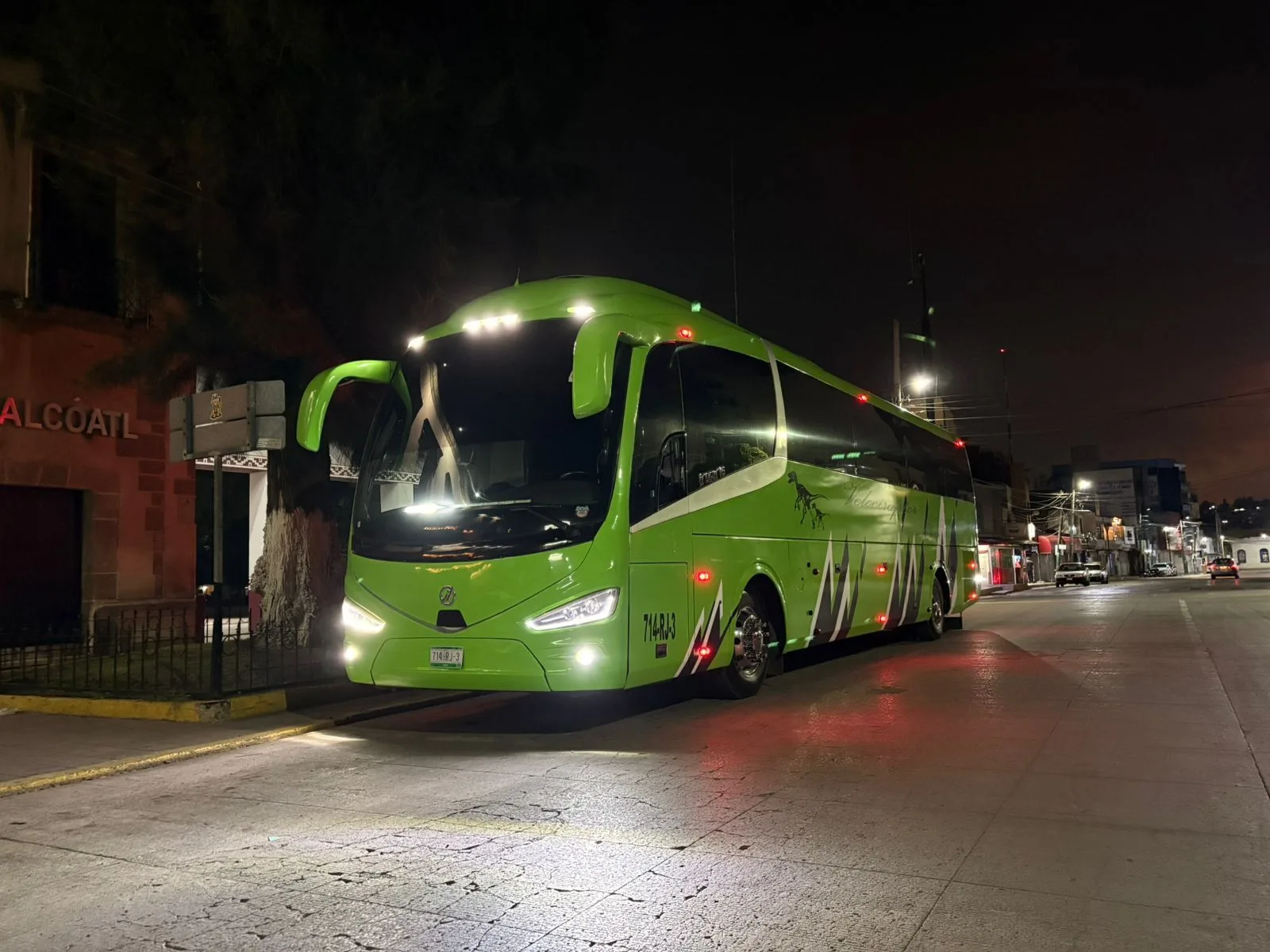 Autobús Irizar i6 verde circulando de noche con sus luces encendidas